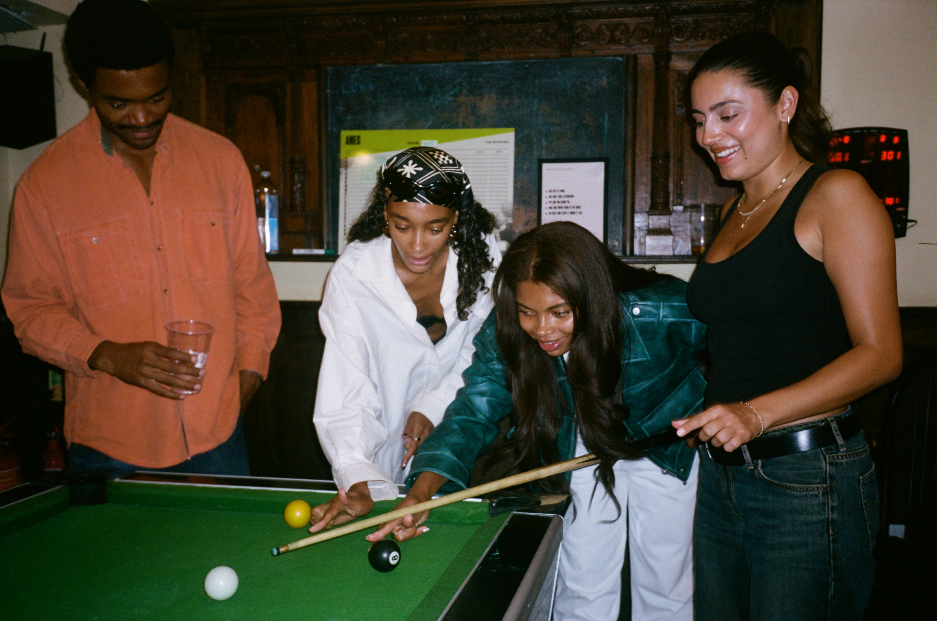 Four people around the pool table at AMES, one lining up a shot